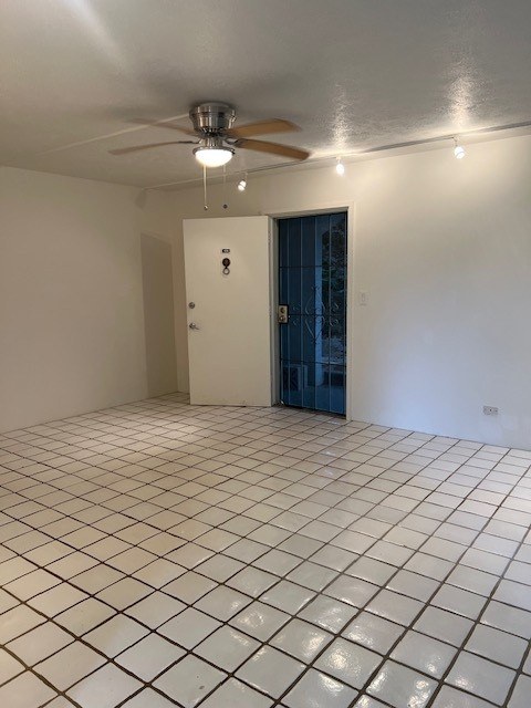 A room with a ceiling fan and tiled floor.